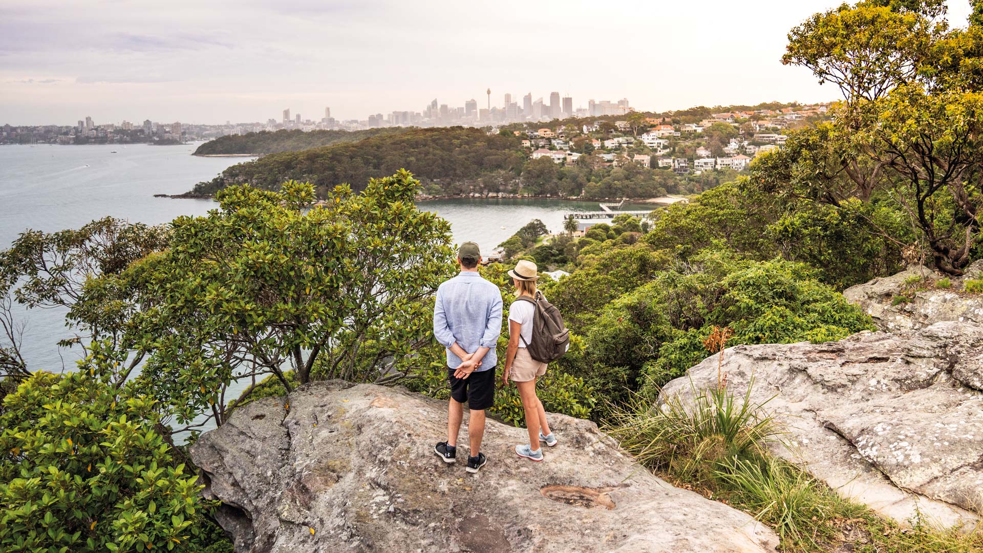 Couple standing on a rock at Georges Heights, admiring the view of Chowder Bay and Sydney Harbour.