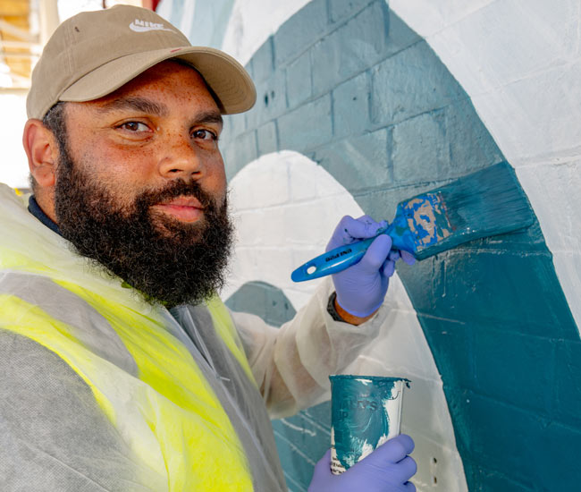 Dennis Golding painting the Around the Curve artwork mural at Sub Base Platypus.